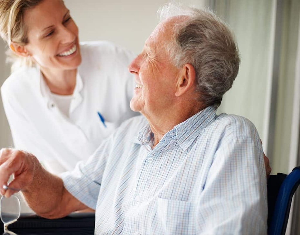 Older Gentleman Patient in Wheelchair Laughing with Female Doctor