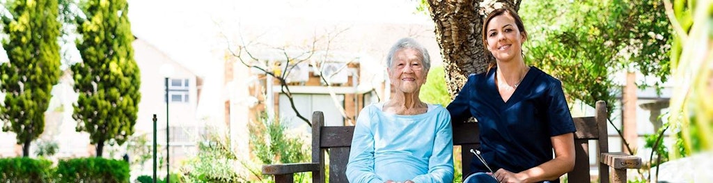 Elderly Patient and Female Nurse Smile at the Camera Outdoors