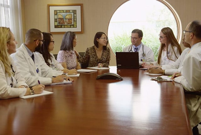 Médicos reunidos alrededor de una mesa de reuniones conversando