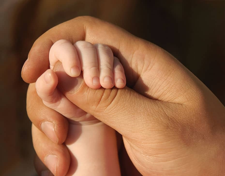 Primer plano de un padre sosteniendo la mano de su bebé