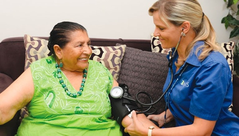 Miembro del personal del sistema de salud de MJHS le toma la presión arterial a un paciente sonriente