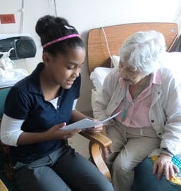 Una joven le lee a una paciente mayor
