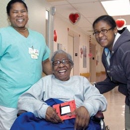 Paciente en silla de ruedas sonríe con una enfermera y una joven