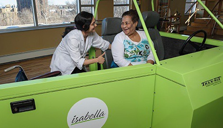 Una cuidadora de Isabella ayuda a una mujer mayor a sentarse en una silla de ruedas