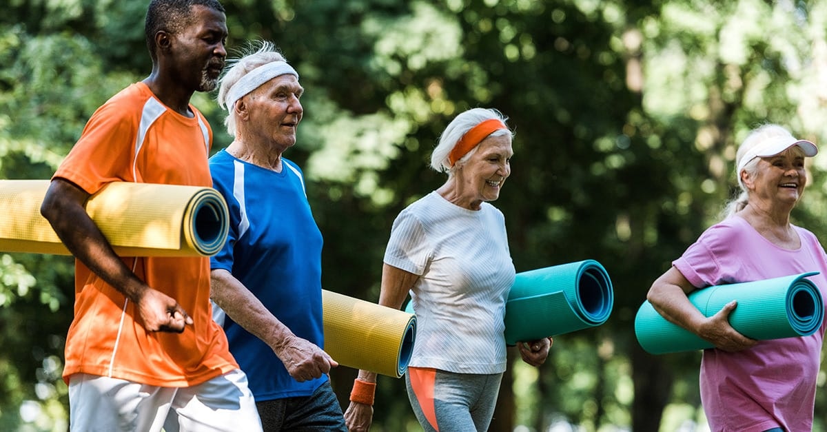 Group of elderly people carrying exercise mats