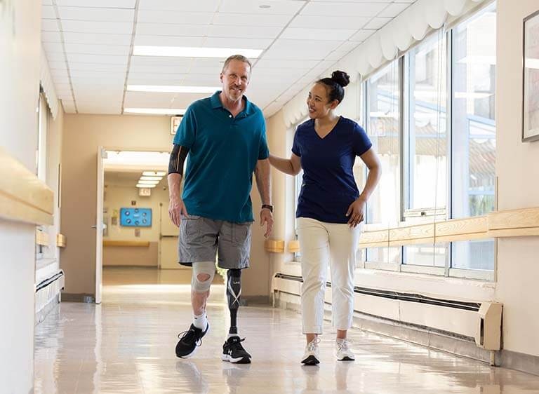 The doctor walks the patient back to a common area, finishing the resident's physical therapy session.